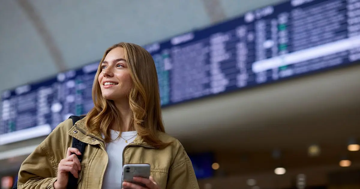 Passenger information at a Deutsche Bahn station Passenger using a smartphone at a Deutsche Bahn station