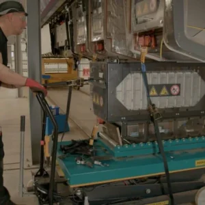 Technicians installing a Turntide battery system on a Hitachi Rail train