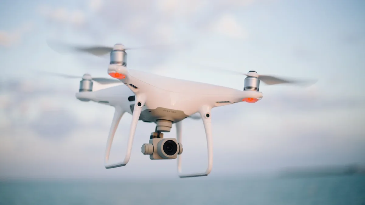 White camera drone flying against a cloudy sky White camera drone flying against a cloudy sky