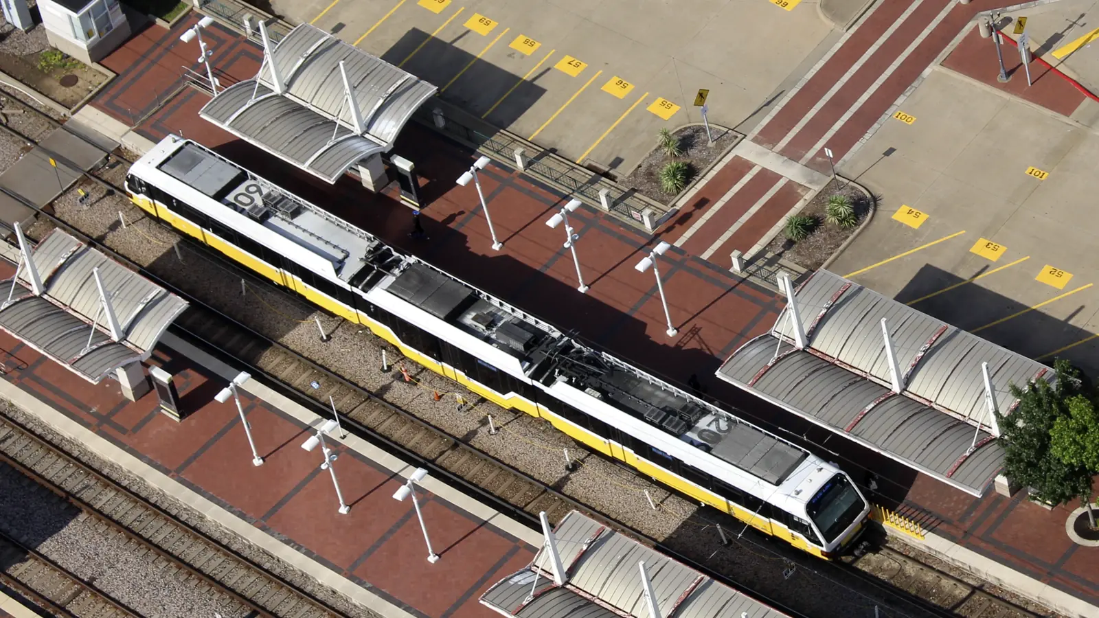Aerial view of a yellow-and-white DART light-rail train at EBJ Union Station in Dallas.