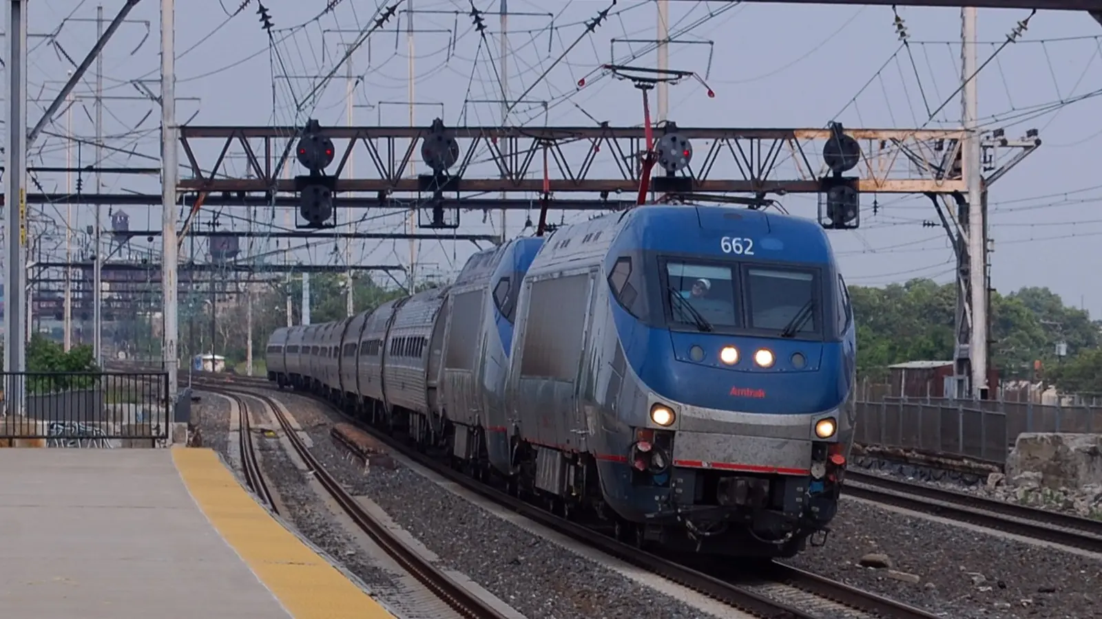 An Amtrak Northeast Regional train approaches North Philadelphia station under overhead wires. An Amtrak Northeast Regional train approaches North Philadelphia station under overhead wires.