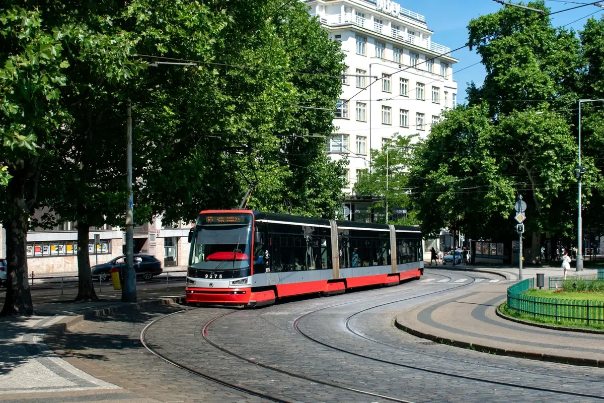 Red and grey Škoda 15T tram travelling around a curved street in Prague