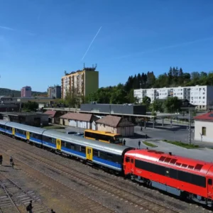 A red diesel locomotive and charter train at Komló station in April 2026