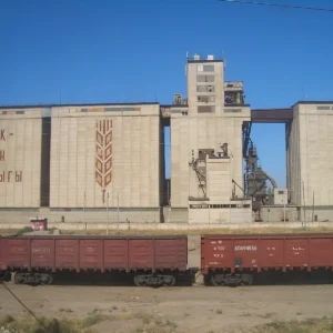 Freight wagons passing a grain elevator near Shu station in Kazakhstan
