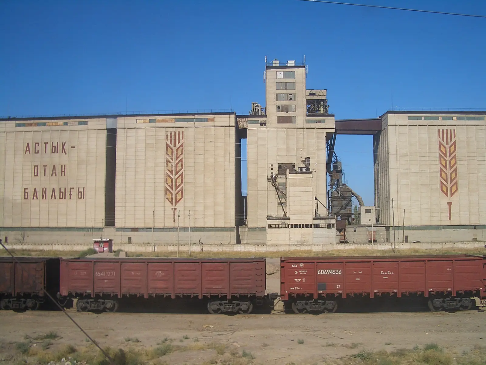 Freight wagons passing a grain elevator near Shu station in Kazakhstan