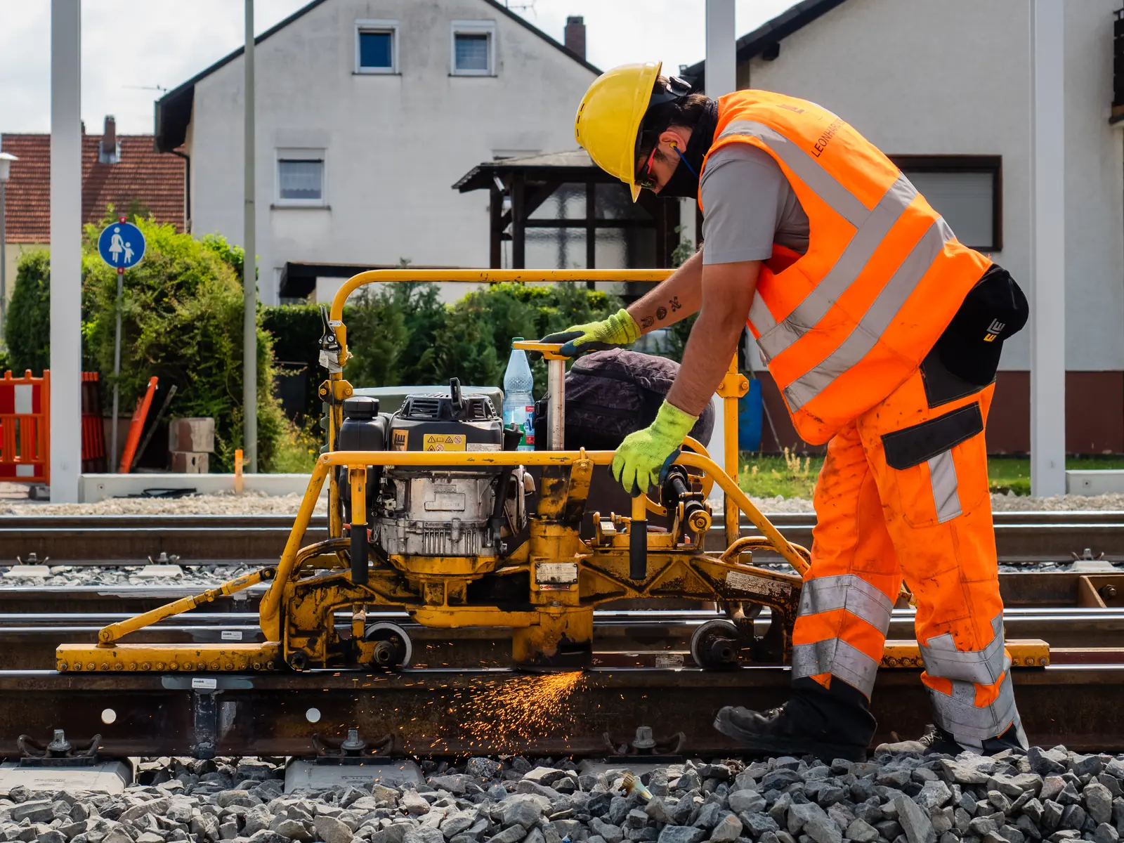Rail worker operating a portable rail-grinding machine on track