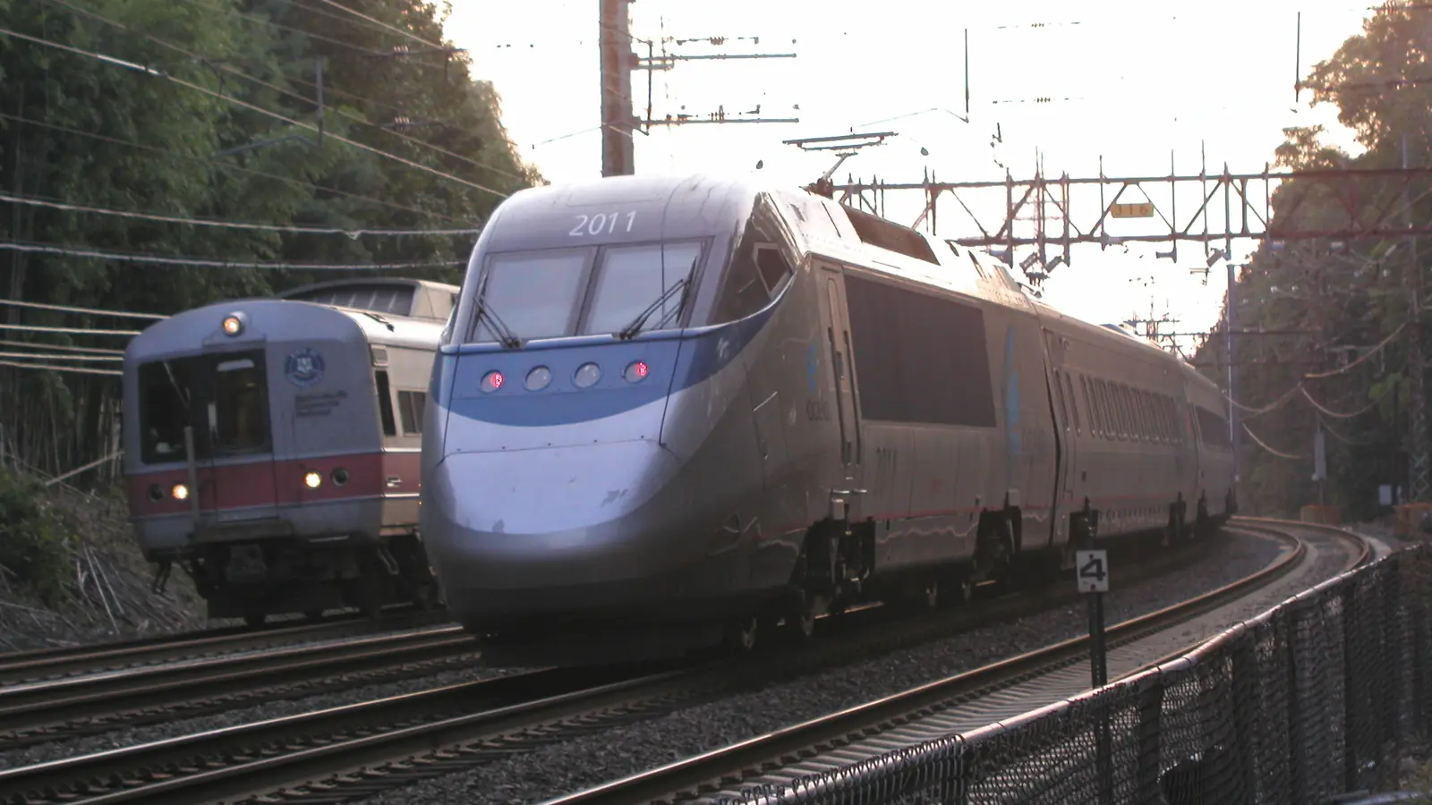 Amtrak Acela train passing a Metro-North railcar on electrified tracks in Greenwich, Connecticut. Amtrak Acela train passing a Metro-North railcar on electrified tracks in Greenwich, Connecticut.