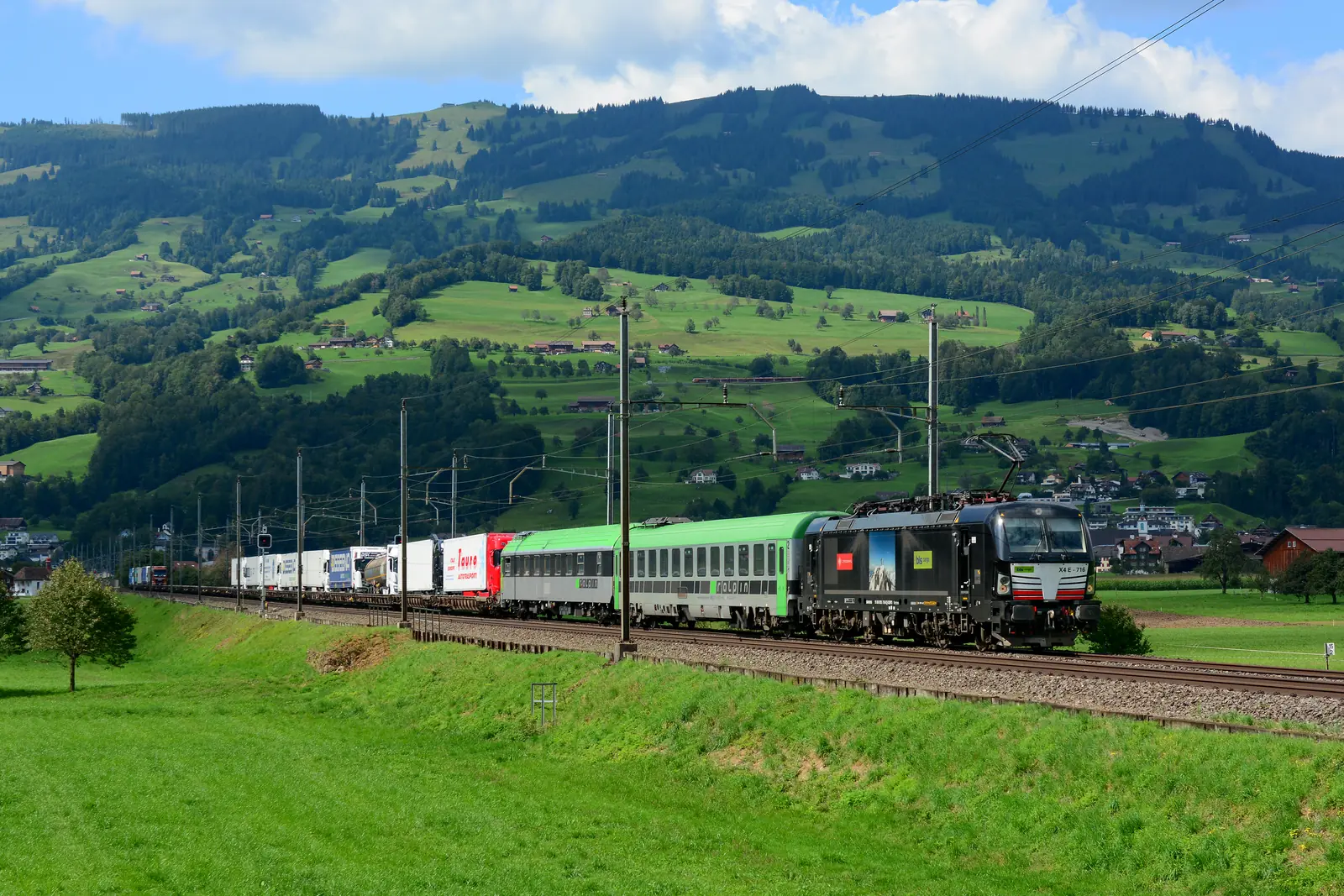 A rolling-road freight train carrying road trailers through a mountain landscape.