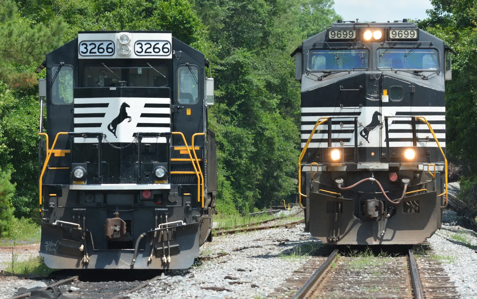 Two black Norfolk Southern diesel locomotives standing on adjacent tracks