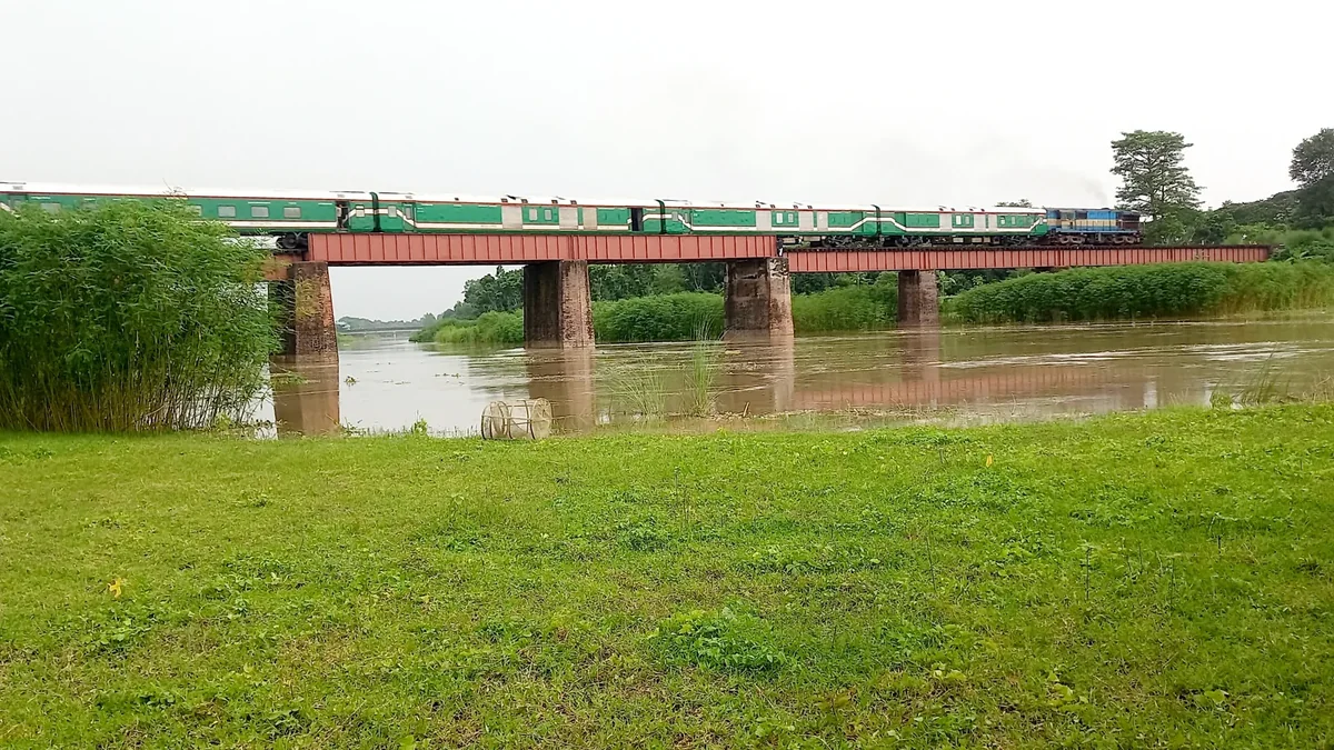 Bangladesh Railway LHB passenger coaches crossing a bridge behind a blue locomotive
