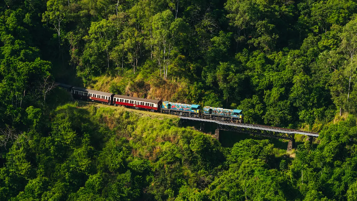 Kuranda Scenic Railway train crossing a bridge through dense rainforest