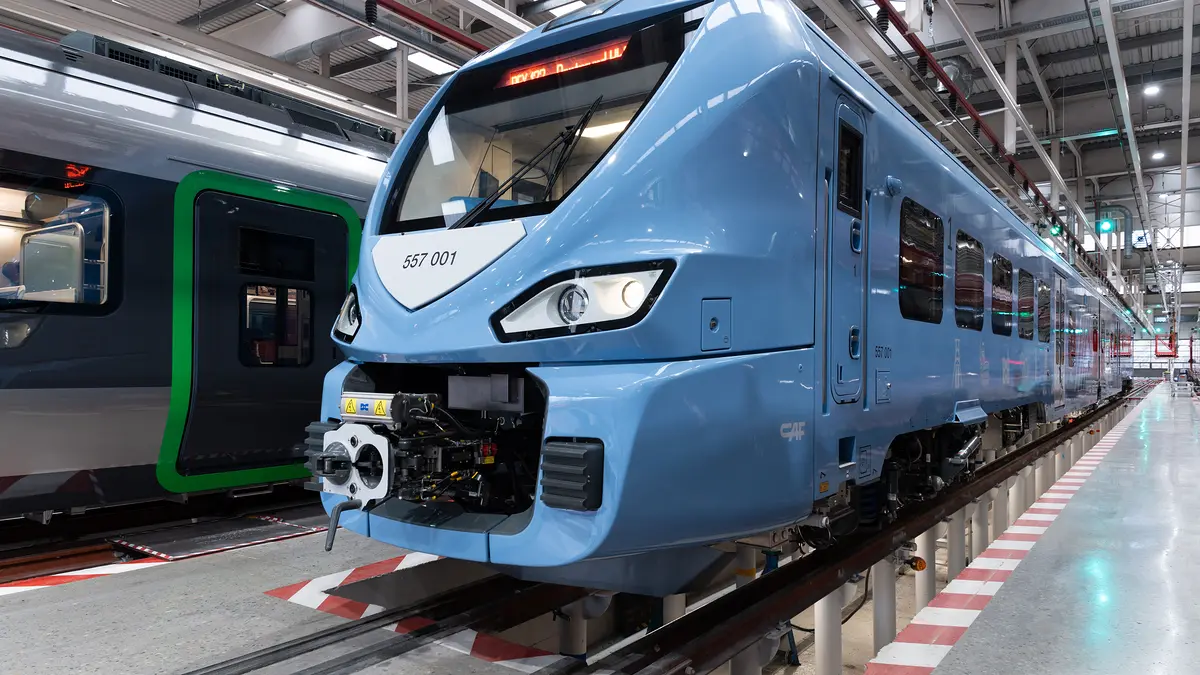 Blue CAF Class 557 battery train inside a maintenance workshop