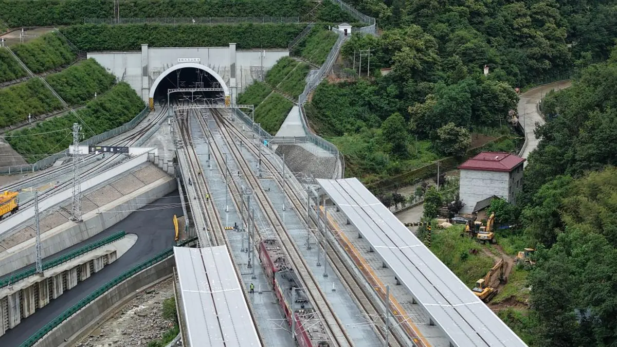 Xi’an–Ankang high-speed railway tracks and a test locomotive approaching a tunnel portal in the Qinling Mountains