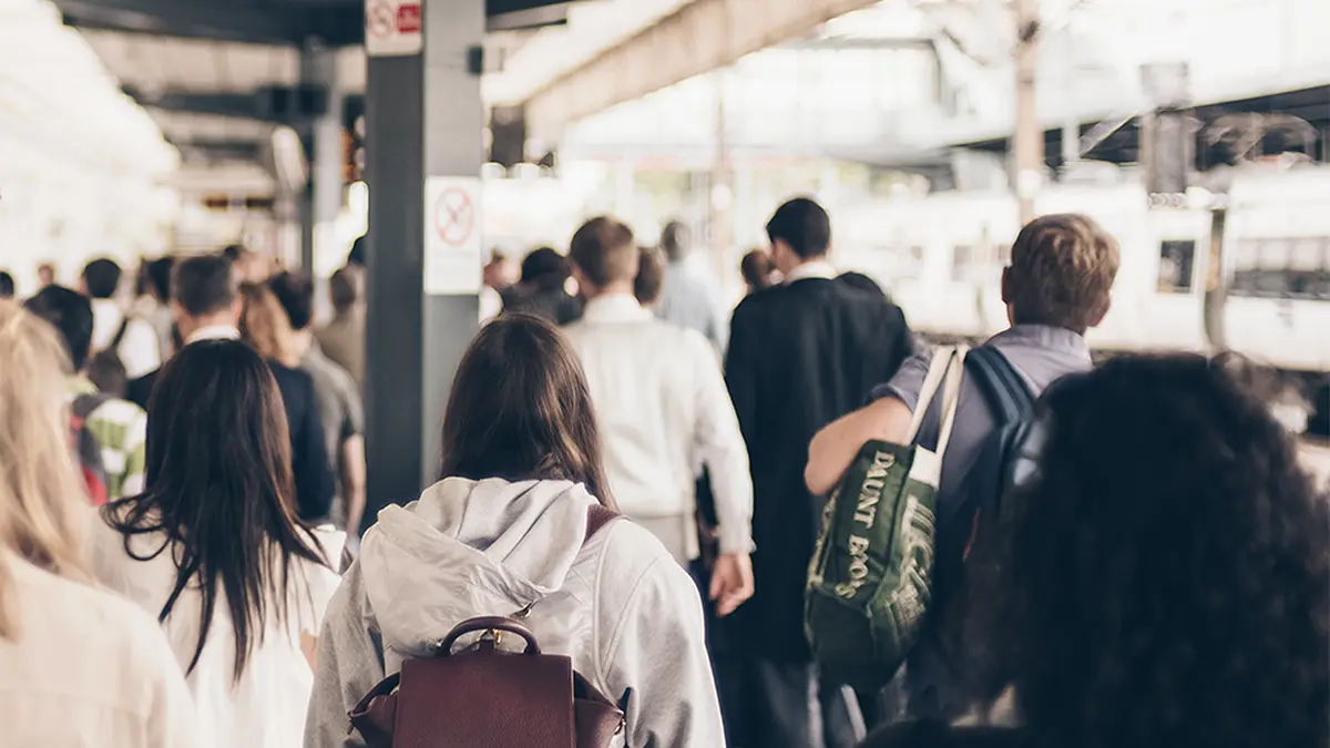Passengers walking along a busy railway platform beside a train