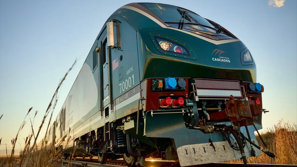 Amtrak Cascades Airo trainset front in green, cream and mocha livery beside grassland tracks