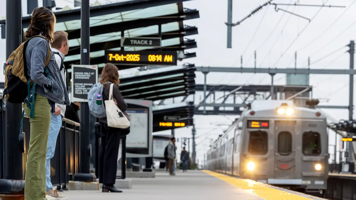 RTD A Line commuter train approaches passengers at 38th•Blake Station in Denver