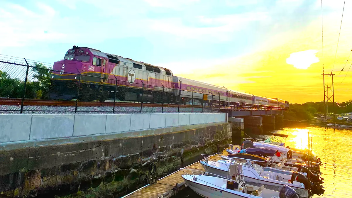 CapeFLYER train crossing a bridge beside a marina at sunset in Wareham