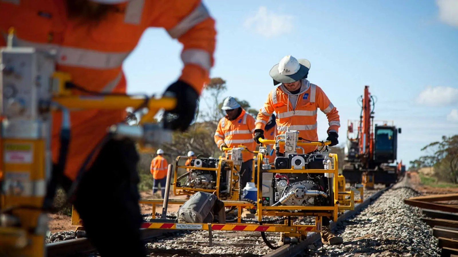 Rail workers operating track maintenance machines on a regional railway line in Victoria