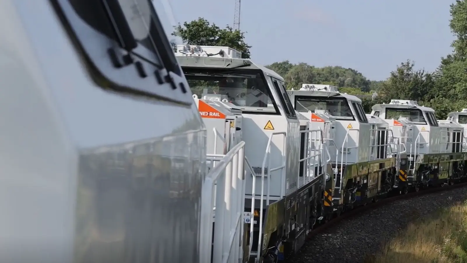 Line of white Nexrail DE18 Smart Hybrid locomotives on curved track