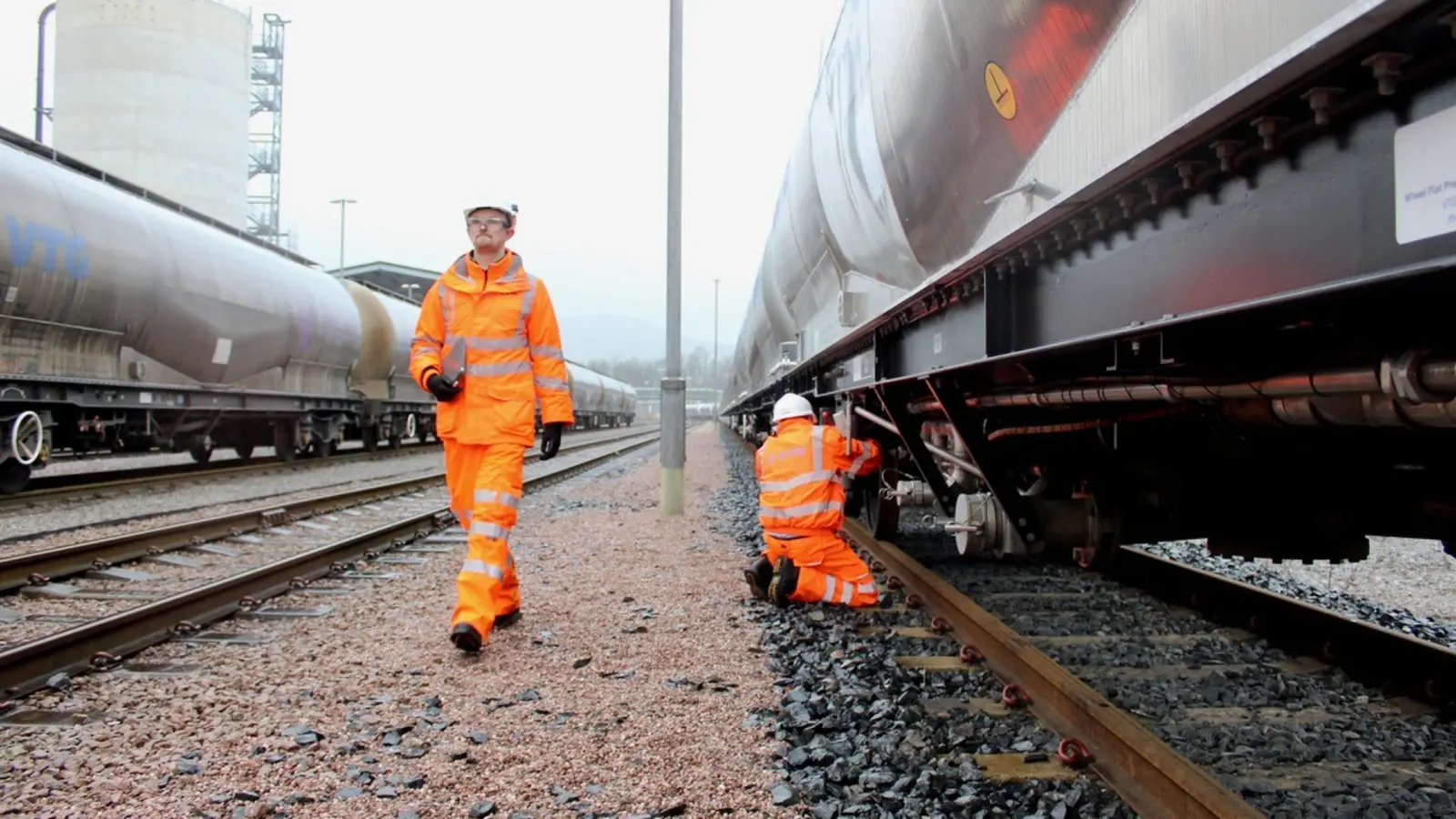 Two rail workers inspect VTG tank wagons at a British rail yard