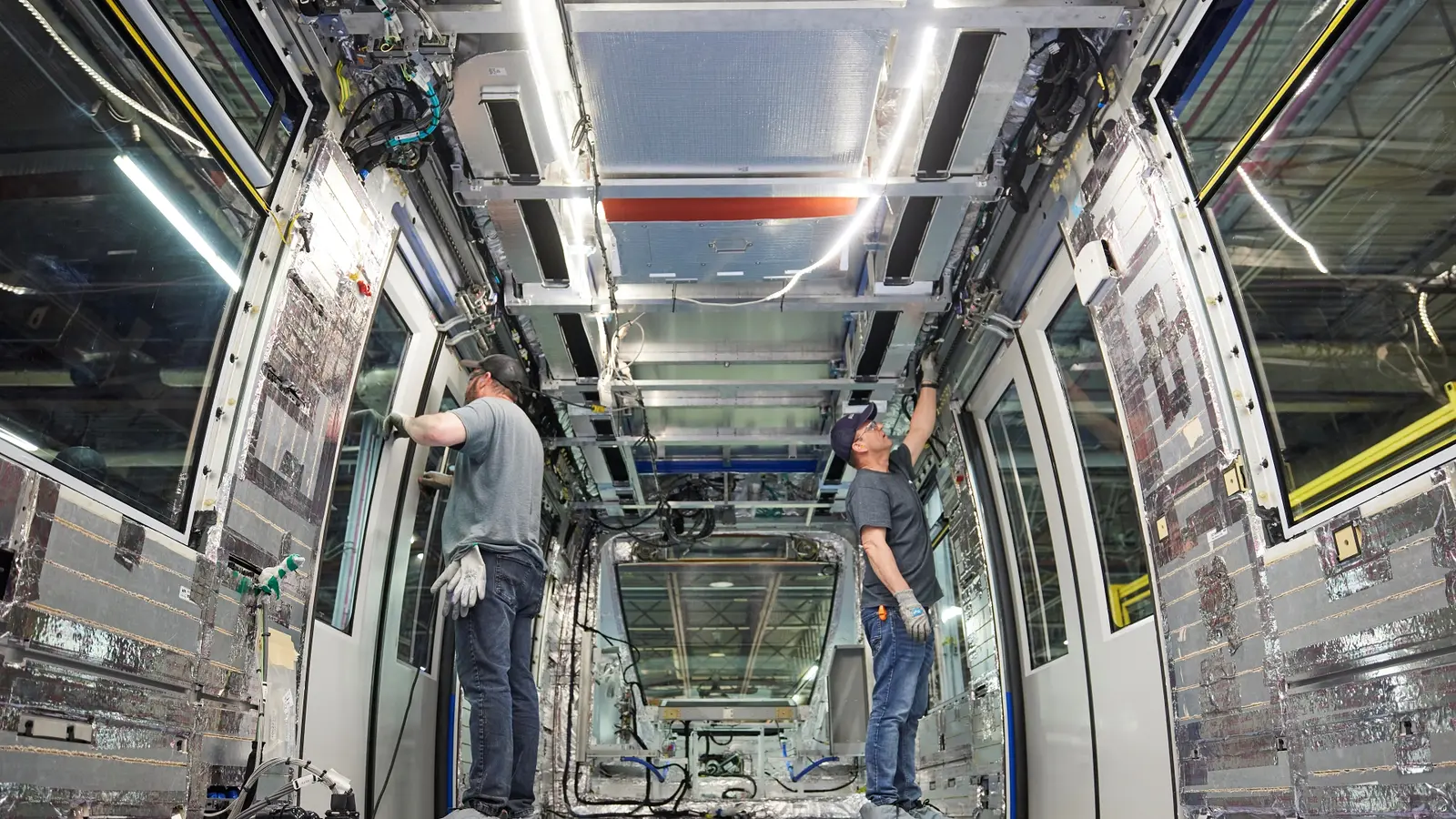 Two workers installing equipment inside a rail vehicle at Alstom’s La Pocatière plant