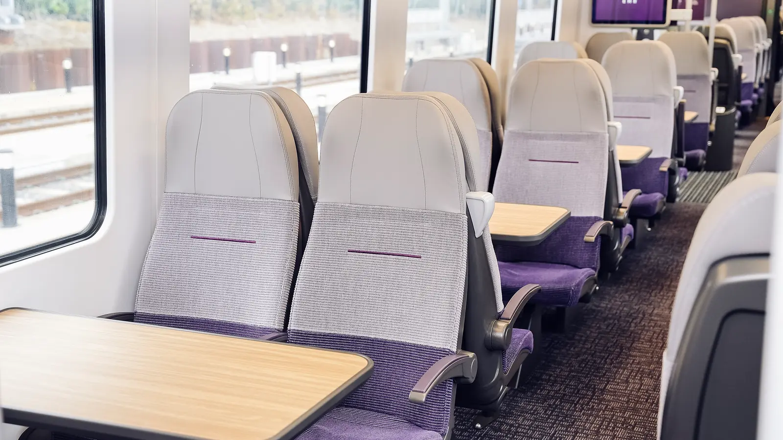 Refurbished Class 360 interior with grey and purple seats, tables and a passenger information screen
