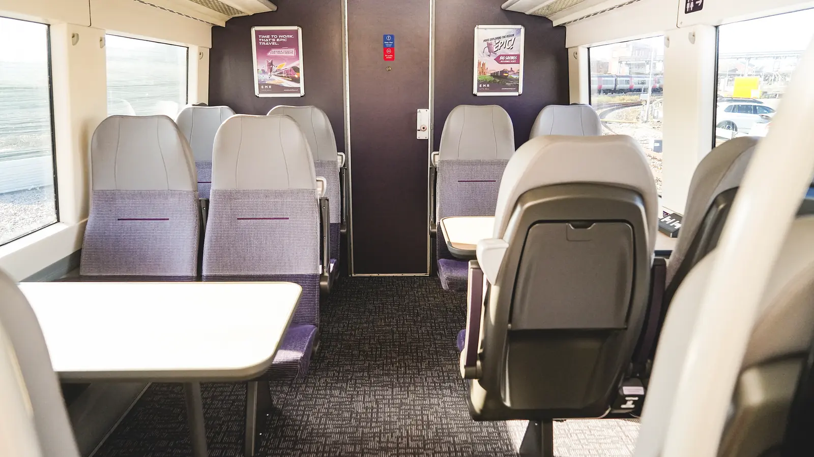Refurbished Class 170 carriage with grey and purple seating arranged around tables