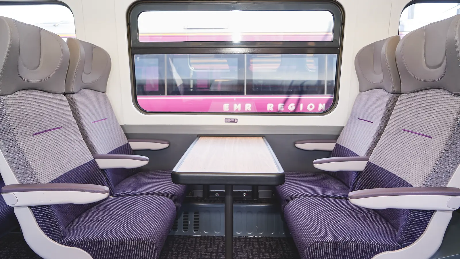 Refurbished Class 158 seats arranged around a table beside a carriage window