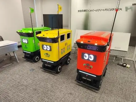 Three JR East mobile trash bin robots in green, yellow and red Shinjukuma wraps