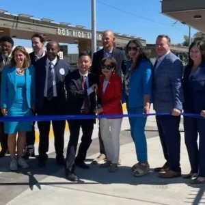 Officials gathered behind a blue ribbon at the completed Dos Rios light rail station