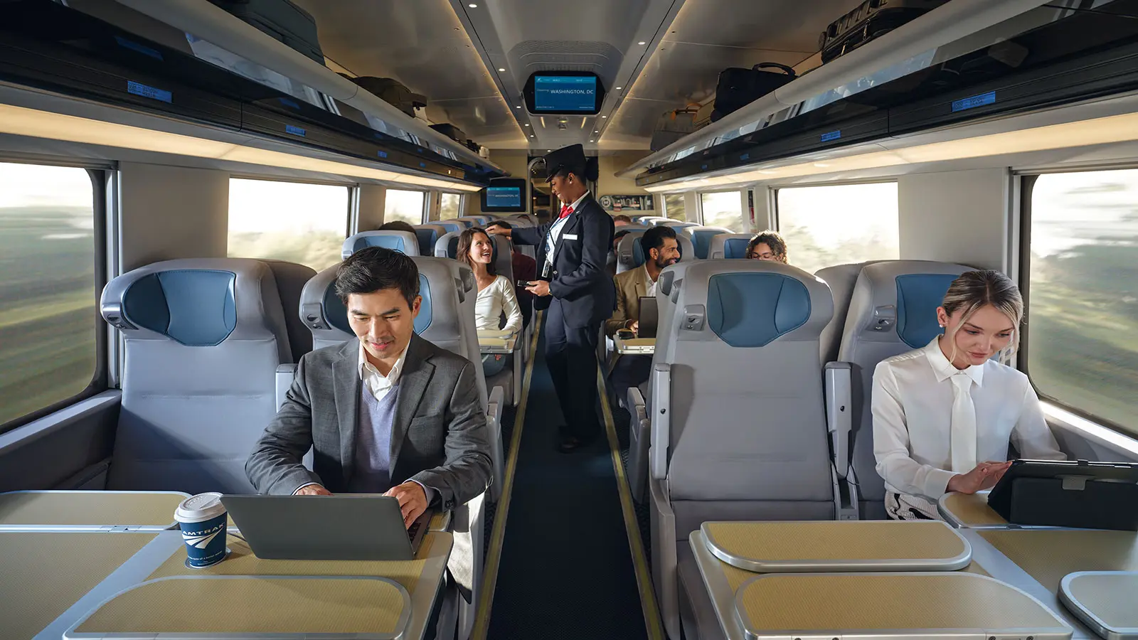 Passengers using laptops and tablets inside a NextGen Acela carriage