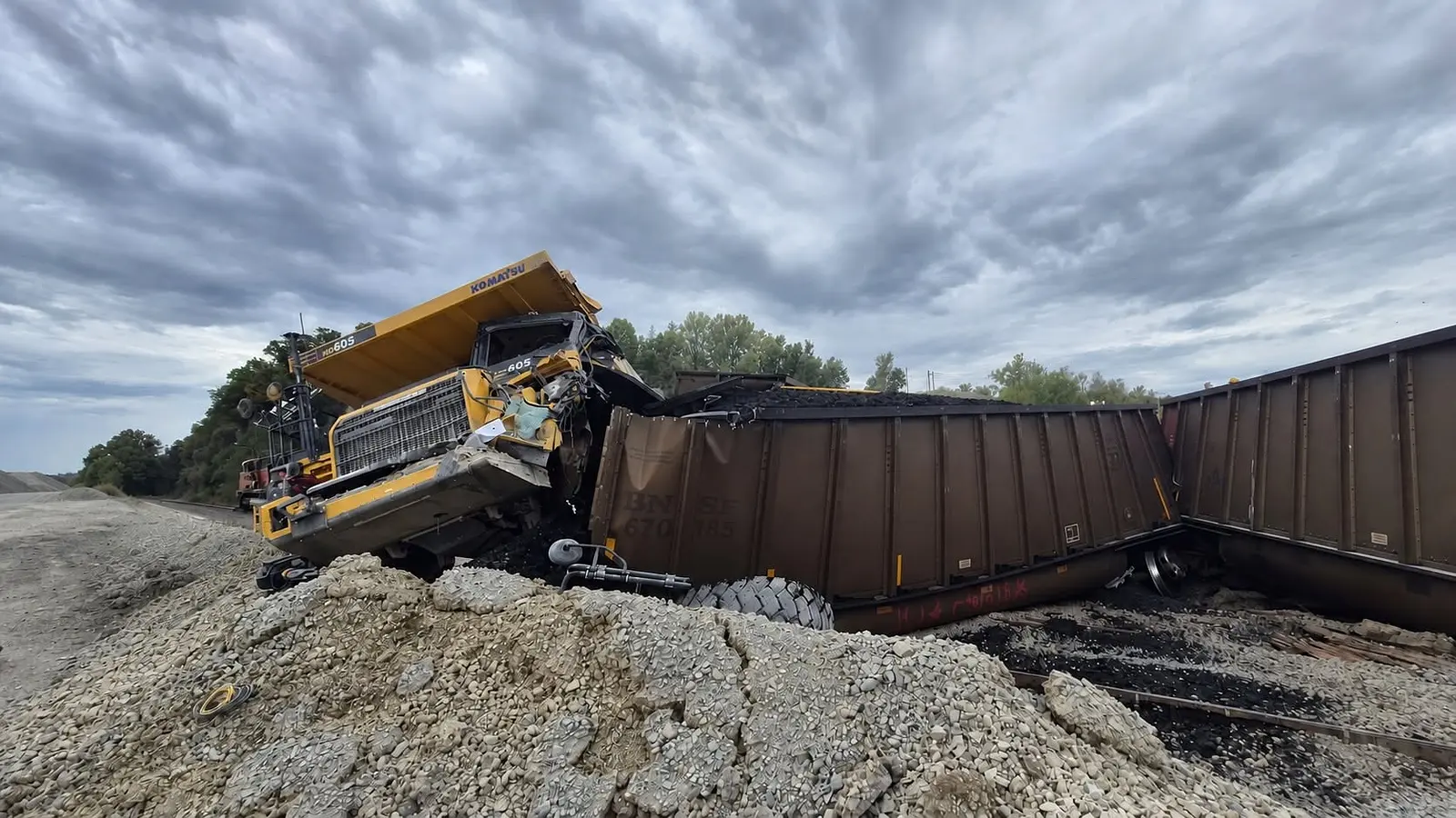 Damaged Komatsu dump truck beside derailed freight cars at South Stone Quarry