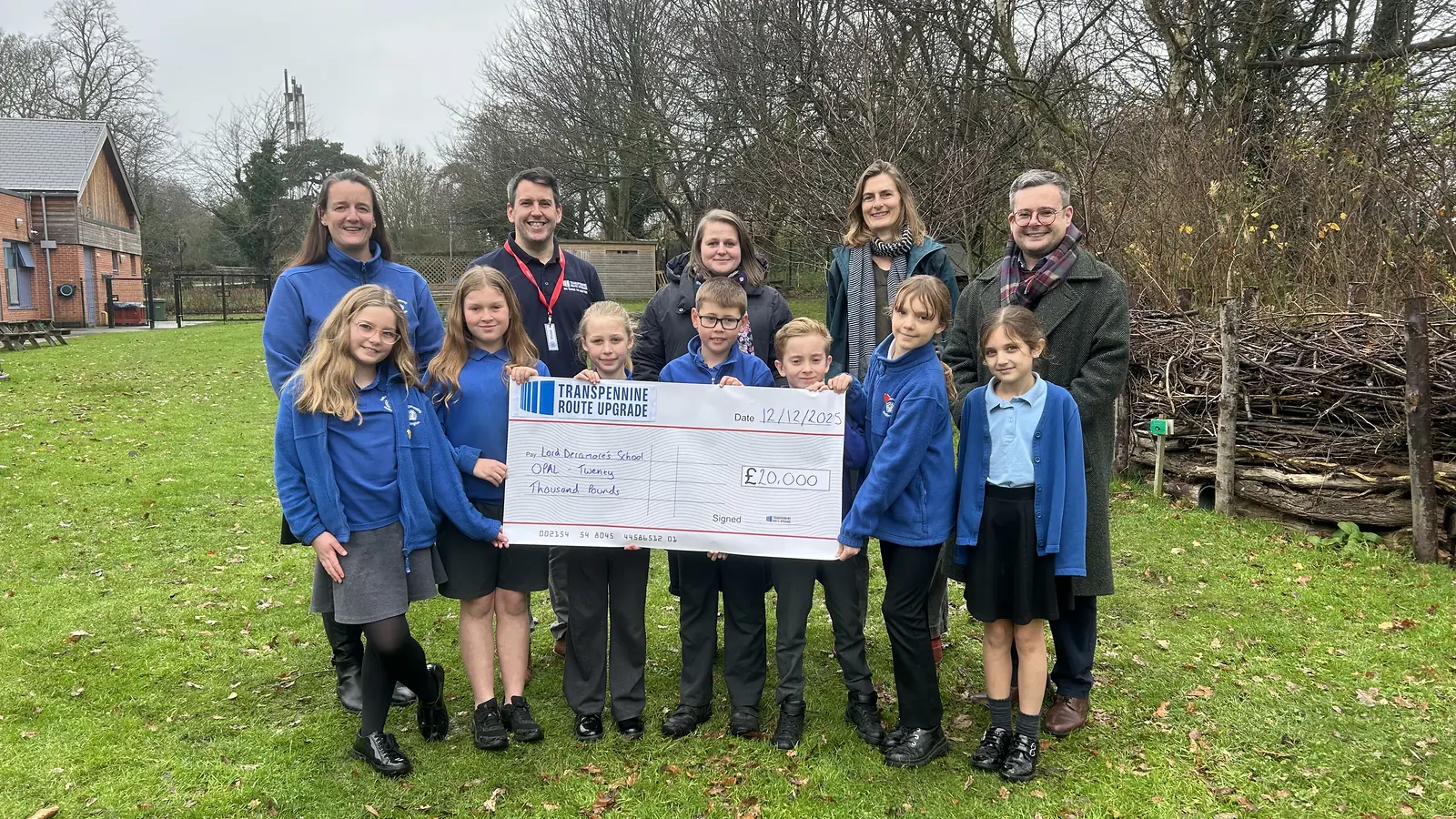 Lord Deramore’s School pupils and adults hold a Transpennine Route Upgrade Community Fund cheque outdoors